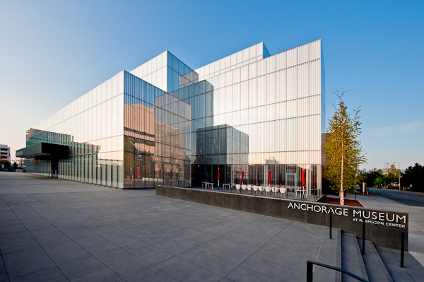 Modern glass exterior of the Anchorage Museum at the Rasmuson Center under a clear blue sky