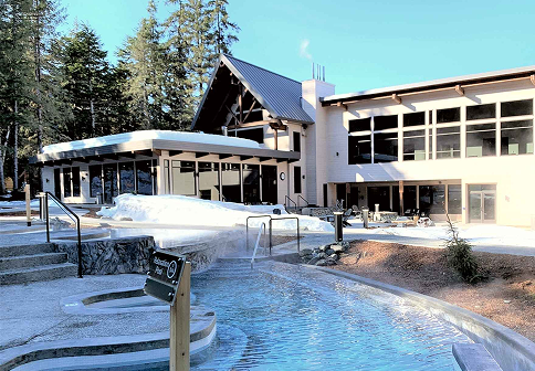 Modern lodge-style building with outdoor hot spring pool surrounded by trees