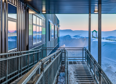 Metal building with accessible ramp overlooking snowy landscape at sunrise