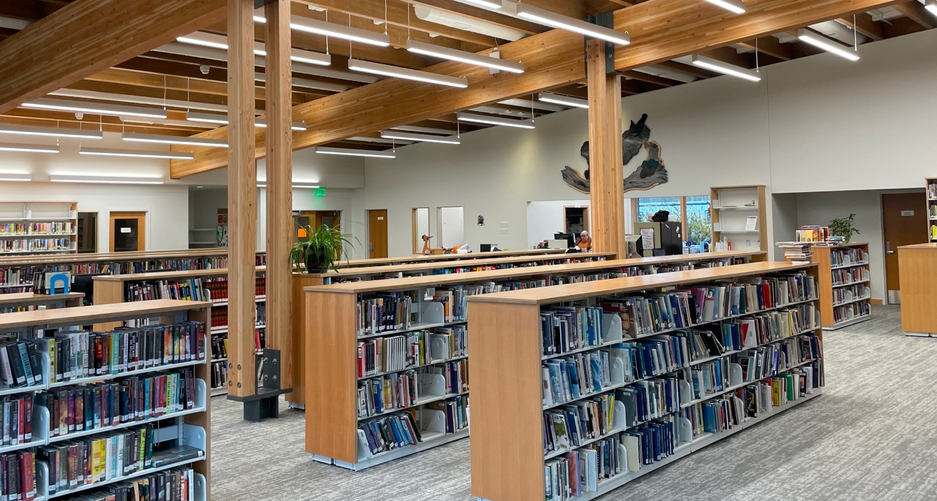 Interior of modern library with wooden beams, bookshelves, and reading area